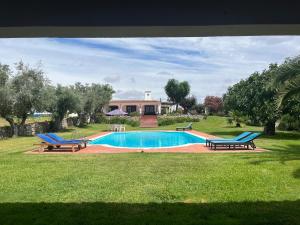 una piscina con 2 sillas azules en un patio en Casa de Campo, Quinta do Funchal, en Arraiolos
