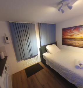 um quarto com uma cama e um quadro na parede em Cozy Garden House kijkduin Beach em Haia