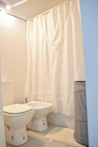 a white bathroom with a toilet and a shower curtain at Agustín I Apart in Paraná