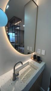 uma casa de banho com um lavatório e um espelho em Studio Cosmopolita - Novo - possui automação em Nova Santa Medianeira