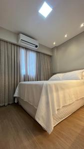 1 dormitorio con cama blanca y ventana en Studio Cosmopolita - Novo - possui automação, en Nova Santa Medianeira