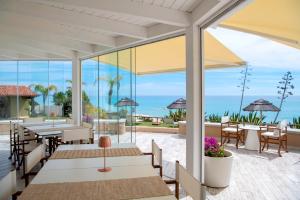 un patio con mesas y sillas y el océano en Villa Escargot Luxury in Costa Rei Beach en Costa Rei
