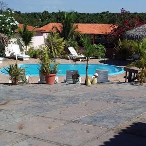 un complexe avec une piscine, des chaises et des palmiers dans l'établissement pousada chykos, à Barreirinhas