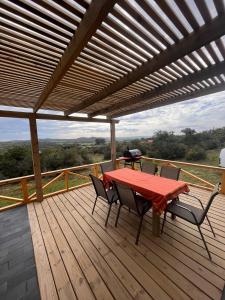 una terraza de madera con mesa y sillas. en Cabaña Los Ceibos., en Villa Serrana