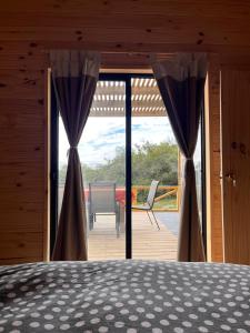 1 dormitorio con 1 cama y puertas correderas de cristal en Cabaña Los Ceibos., en Villa Serrana