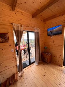 Habitación con una gran puerta de cristal en una cabaña de madera. en Cabaña Los Ceibos., en Villa Serrana