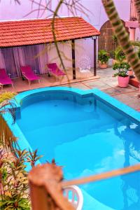 a large blue swimming pool in a yard with pink chairs at Hotel Santa Lucía in Mérida