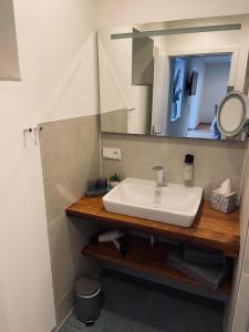 La salle de bains est pourvue d'un lavabo et d'un miroir. dans l'établissement HALBSTÜCK - Ferienwohnungen am Kropsbachpark, à Sankt Martin