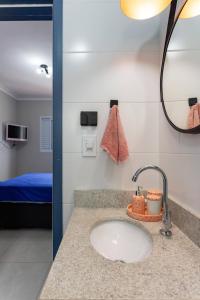 ein Bad mit einem Waschbecken und einem Spiegel in der Unterkunft Apartamento na Praia Grande II - Pé na Areia in Praia Grande