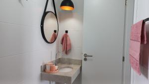 ein Bad mit einem Waschbecken und einem Spiegel in der Unterkunft Apartamento na Praia Grande II - Pé na Areia in Praia Grande