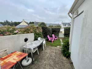 een kleine patio met roze stoelen en een tafel bij Maisonnette de bord de mer in Guidel