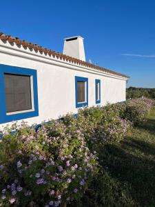 Casa blanca con ventanas azules y flores en Casa de Campo, Quinta do Funchal, en Arraiolos