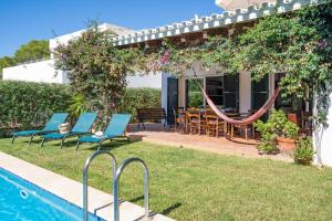 a house with a swimming pool with chairs and a hammock at Chalet en Biniancolla con piscina y jardin in Sant Lluis