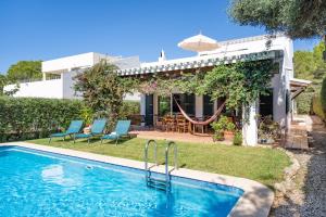 a swimming pool in front of a house at Chalet en Biniancolla con piscina y jardin in Sant Lluis