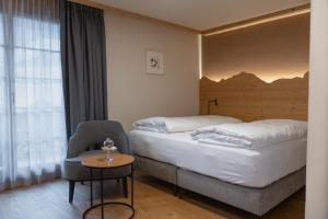 una habitación de hotel con 2 camas y una silla en Hotel Alpenland, en Gstaad
