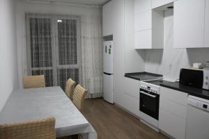a kitchen with white cabinets and a table with chairs at ЖК Терра in Almaty