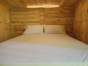 a bed in a wooden cabin with a white bedsheet at Hostel Tropico 20 PDC in Playa del Carmen