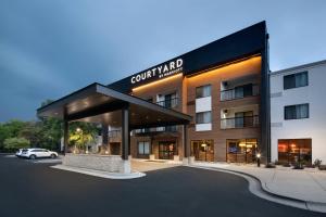 a building with a car parked in a parking lot at Courtyard Grand Rapids Airport in Grand Rapids