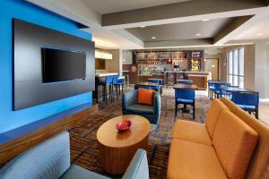 a hotel lobby with chairs and a tv and a bar at Courtyard Grand Rapids Airport in Grand Rapids