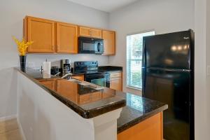 cocina con nevera negra y armarios de madera en Encantada Resort Vacation Townhomes by IDILIQ, en Kissimmee