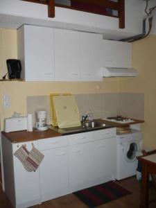 a kitchen with white cabinets and a sink and a washing machine at Azur Sancy Skis aux pieds in Le Mont-Dore +4 photos