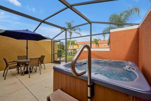 基西米的住宿－Encantada Resort Vacation Townhomes by IDILIQ，庭院内的热水浴池配有桌子和遮阳伞