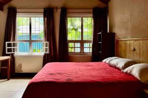 um quarto com uma grande cama vermelha e 2 janelas em Casa I’x (Jaguar) em San Juan La Laguna