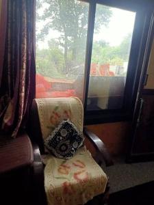 einen Stuhl mit einem Kissen neben einem Fenster in der Unterkunft home sweet home in Bhopal