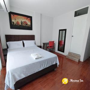 ein Schlafzimmer mit einem weißen Bett und einem roten Stuhl in der Unterkunft Maximus Inn in Sechura