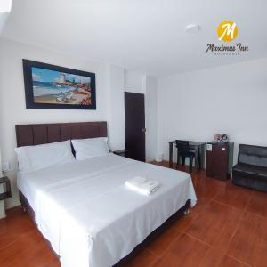 a bedroom with a white bed and a table and a couch at Maximus Inn in Sechura