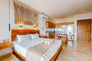 a bedroom with a large bed and a kitchen at Adora Tulum 406 at Av Kukulkan in Tulum