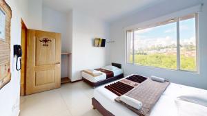 a small bedroom with two beds and a window at Hotel Villa Colonia in Marinilla