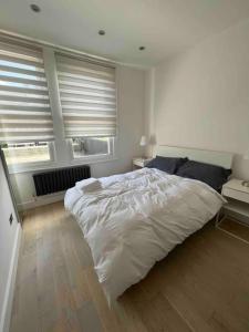 - une chambre avec un grand lit blanc et 2 fenêtres dans l'établissement Cozy 2 Bed Room Tufnell Park Haven, à Londres
