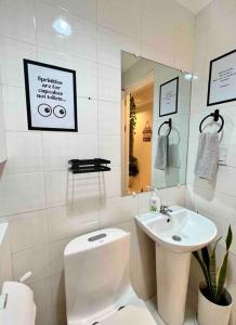La salle de bains est pourvue d'un lavabo, de toilettes et d'un miroir. dans l'établissement Charm’s Place, à Olongapo
