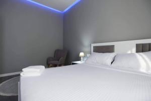 a bedroom with a large white bed and a chair at Centrally located apartment in Korçë