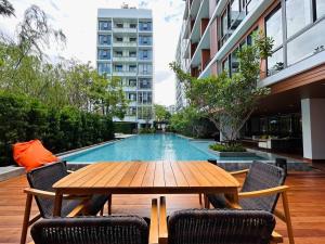 a wooden table and chairs in front of a swimming pool at Tierra Residences in Bangkok