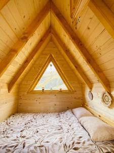 a bed in a wooden room with a window at Kapetanovo Jezero Bungalov in Podgorica