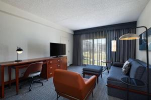 a hotel room with a desk and a couch and a chair at Courtyard Fort Worth University Drive in Fort Worth