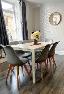 a dining room table with chairs and a vase of flowers at Cozy Cribs near Zipworld, Dare Valley Bike Park, Pen-y-fan & Four Waterfalls Walk in Aberdare