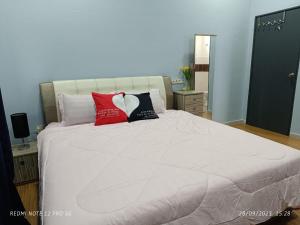 - un lit blanc avec des oreillers rouges et noirs dans l'établissement Loving Homestay, à Kuantan