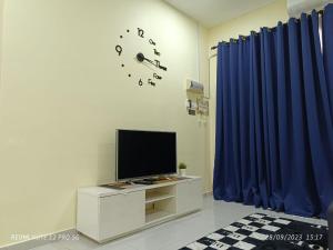 - un salon avec une télévision et des rideaux bleus dans l'établissement Loving Homestay, à Kuantan
