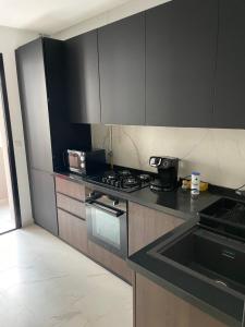 a kitchen with black cabinets and a stove and a sink at Tunis Résidence california in Al Karm