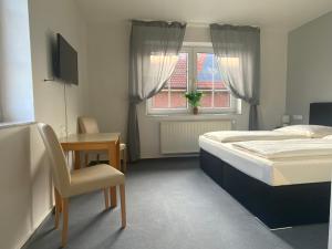 Schlafzimmer mit einem Bett, einem Schreibtisch und einem Fenster in der Unterkunft Berghotel Sülbeck in Nienstädt