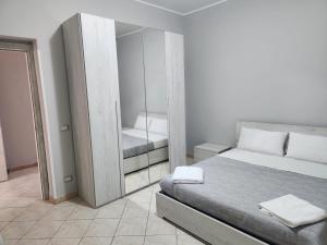 a white bedroom with a bed and a mirror at Nautilus Affittacamere in Focene