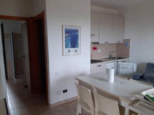 a kitchen with a white table and white cabinets at Stintino - Cala Lupo in Stintino