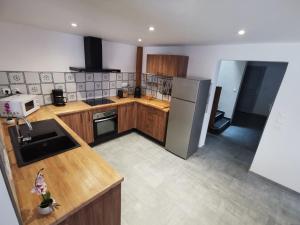 a kitchen with wooden cabinets and a stainless steel refrigerator at Gîte des quatre saisons in Thilay