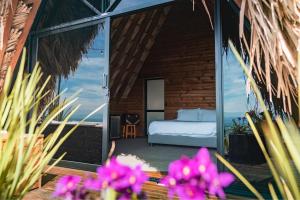 um quarto com uma cama e algumas flores roxas em La Cima Eco Hotel em Buenavista