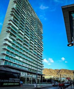 un edificio alto con coches estacionados frente a él en EcoApart Antofagasta, en Antofagasta