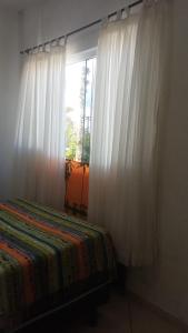 a bedroom with a bed and a window with curtains at Pousada Encantadas in Pontal do Paraná