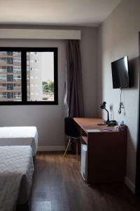 a hotel room with a desk and a bed and a window at Comfort Hotel Presidente Prudente in Presidente Prudente